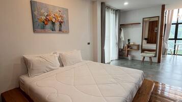 Un dormitorio con una cama grande, un cuadro en la pared, un banco de madera y vistas a un balcón.