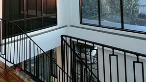 A modern interior with a staircase, large windows, and a chandelier. - Mei Nai Home (Pua)