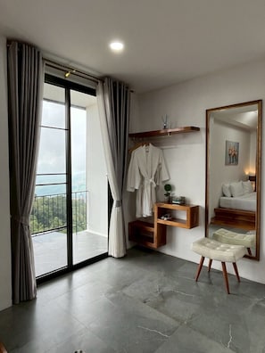 A modern bedroom with a large mirror, a robe, and a view of the outdoors. - Mei Nai Home (Pua)
