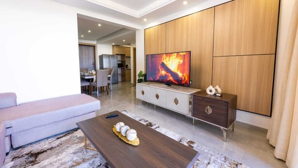 Uma sala de estar moderna com televisão de tela plana, um sofá, uma mesa de centro e um armário de madeira.