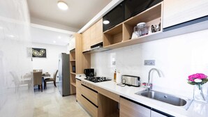 Uma cozinha moderna com bancada branca, pia de aço inoxidável e armários de madeira.