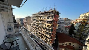 Ein Balkon mit Tisch und Stühlen, mit Blick auf ein mehrgeschossiges Gebäude mit Balkonen.