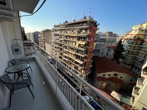 Ein Balkon mit Blick auf ein mehrstöckiges Gebäude, einem Tisch und Stühlen.
