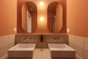 Een badkamer met twee wasbakken, een spiegel en wandlampen.