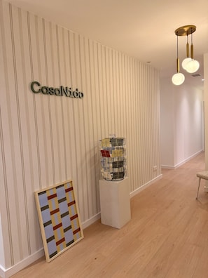 A hallway with a striped wall, a framed artwork, a display of postcards, and a hanging light fixture. - Casa Nido Diagonal - Shared room (Barcelona)