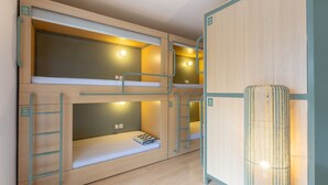 A bunk bed room with a ladder, a pull-out desk, and a wall-mounted lamp.