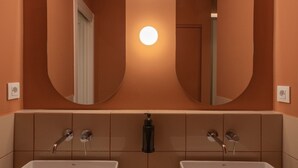 A bathroom with two sinks, a large mirror, and a wall-mounted light.