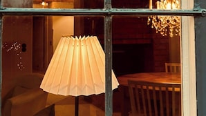 Ein Fenster mit Blick auf einen Innenraum, eine Lampe und eine Chandelier.