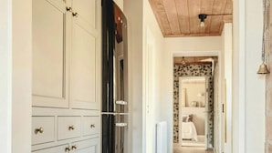 Ein Flur mit Holzboden, weißen Schränken und einem schwarzen Kühlschrank.