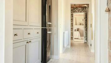 Un couloir doté d’un plancher en bois, de meubles blancs et d’un réfrigérateur noir.