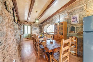 A rustic stone kitchen with wooden furniture, a large wooden table, and a refrigerator. - Villa Fontanelle With Garden (Ugento)