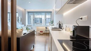 A modern kitchen with a central island, a built-in stove, and a window providing natural light. - Modern Studio in Central Psyri King Bed (Athina)