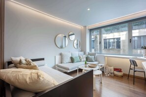 Une chambre moderne avec un lit, un canapé, une petite table et une fenêtre donnant sur un paysage agréable.