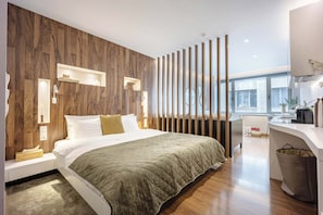 Una habitación de hotel moderna con una pared de acento de madera, una cama grande, un escritorio y vistas a la ciudad.