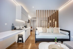 A modern kitchen with a built-in island, a dining area with a round table, and a bedroom with a bed and bedside tables. - Modern Studio in Central Psyri King Bed (Athina)
