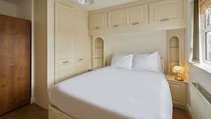 A bedroom with a bed, nightstands, a lamp, a wooden wardrobe, and a window with curtains. - Host Stay - Urban Nest LIV (Liverpool)
