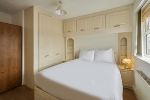 A bedroom with a bed, nightstands, a lamp, a wooden wardrobe, and a window with curtains. - Host Stay - Urban Nest LIV (Liverpool)