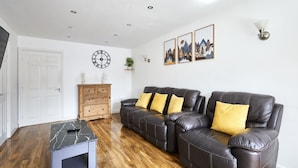 A living room with a sofa set, a clock, wall art, and a small table. - Host Stay - Urban Nest LIV (Liverpool)
