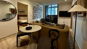 A modern living room with a sofa, chairs, a small table, a TV, and a large window. - w Warm 2BR w AC in the Heart of Cuauht moc (Mexico City)