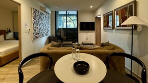 A modern hotel room with a sofa, a dining table with chairs, a TV, and artwork on the walls. - w Warm 2BR w AC in the Heart of Cuauht moc (Mexico City)
