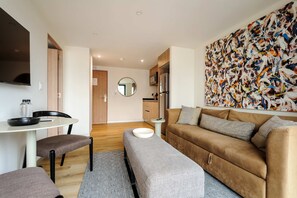 Ein modernes Wohnzimmer mit einer Couch, einem Esstisch und einer Küche im Hintergrund.