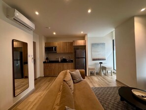 Ein modernes Wohnzimmer mit einer Couch, einem Esstisch und einer Küchenzeile mit Holdekor und Geräten.