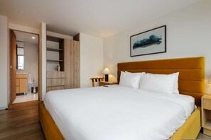 Ein Hotelzimmer mit einem großen Bett, einem Nachttisch mit Lampe, einem Kleiderschrank und einem Bild an der Wand.