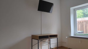 A room with a window, a radiator, and a TV mounted on the wall. - Ferinhaus near the coast (Großenwiehe)