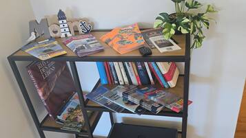 A bookshelf with various books and magazines, a laptop, and a small potted plant.