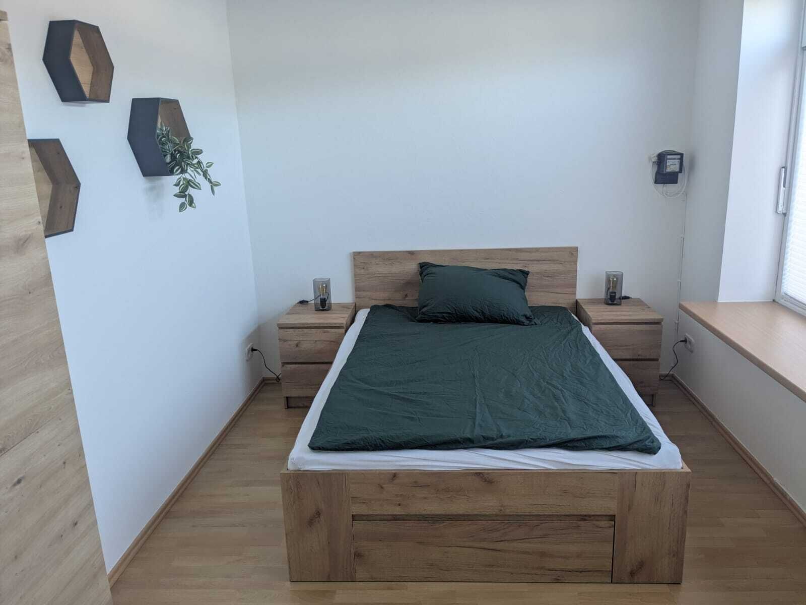Une chambre à coucher avec un lit en bois, des tables de chevet, une fenêtre et des motifs géométriques décorant les murs.