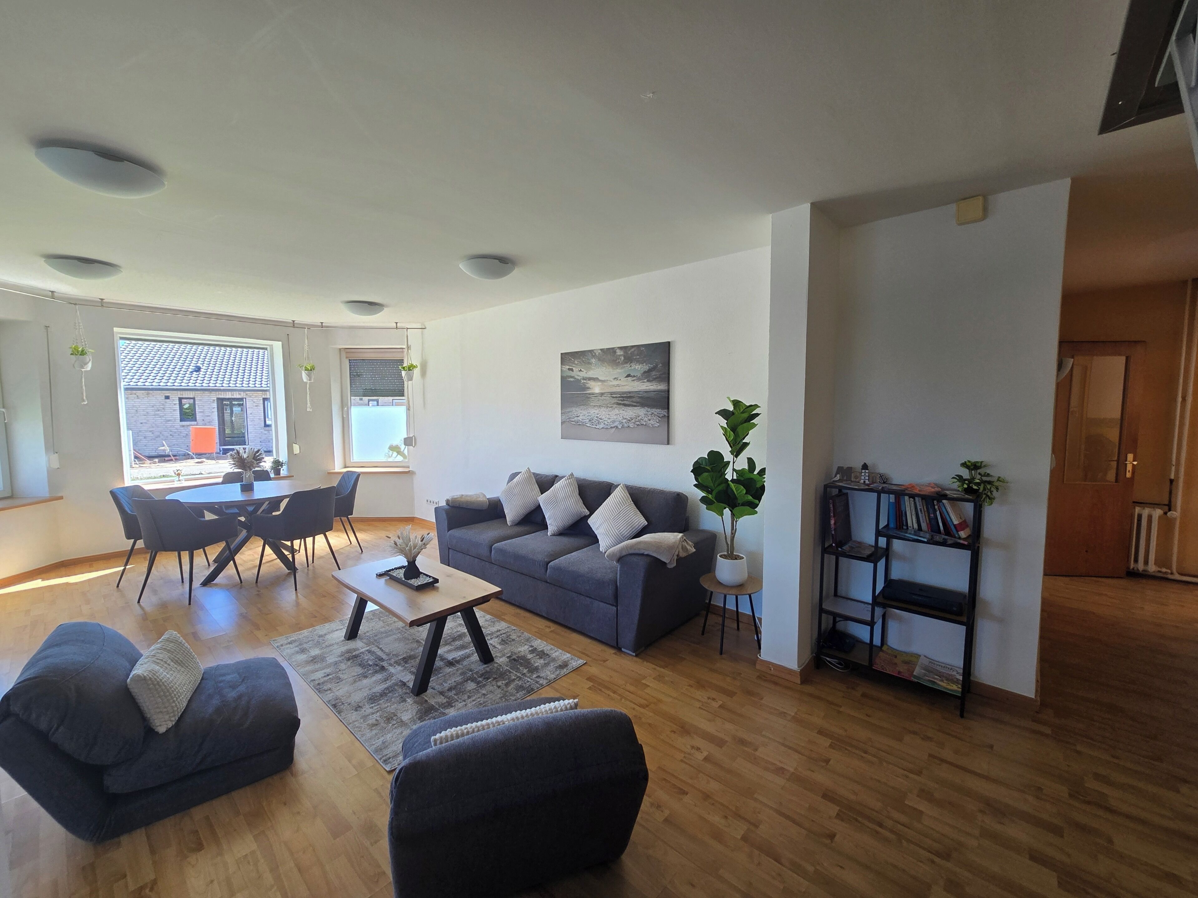 Una sala de estar moderna con un sofá gris, una mesa de centro y un comedor con mesa y sillas.