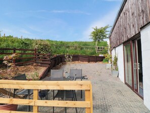 A patio with a wooden table and chairs, a gravel path, and a wooden fence. - Grove Stables House (Yarm)