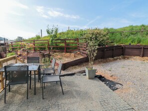 A patio area with a table and chairs, a small garden bed, and a wooden fence. - Grove Stables House (Yarm)