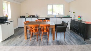A compact kitchen with a dining table, chairs, and a black cabinet. - Grove Stables House (Yarm)