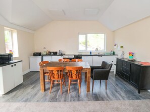 A compact kitchen with a dining table, chairs, and a black cabinet. - Grove Stables House (Yarm)