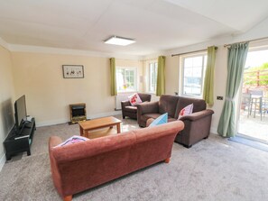 A living room with a sofa, armchairs, a coffee table, a TV, and a fireplace. - Grove Stables House (Yarm)