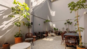 Eine Terrasse mit Sitzgelegenheiten, Tischen und Topfpflanzen.