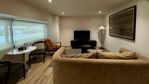 Ein modernes Wohnzimmer mit einer Couch, einem Fernseher, einer Lampe und einem Tisch mit Flaschen.