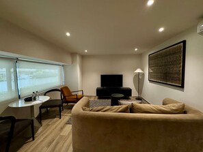 Ein modernes Wohnzimmer mit einer Couch, einem Fernseher, einer Lampe und einem Tisch mit Flaschen.