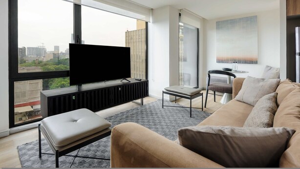 A modern living room with a large window, a flat-screen TV, a sofa, and a small table. - w Amazing 2BR w/ AC in the Heart of Cuauhtémoc (Mexico City)