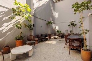 Eine Terrasse mit Sitzgelegenheiten, Tischen und Topfpflanzen.