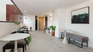 Un moderno vestíbulo de hotel con una mesa redonda, un banco y plantas en macetas.