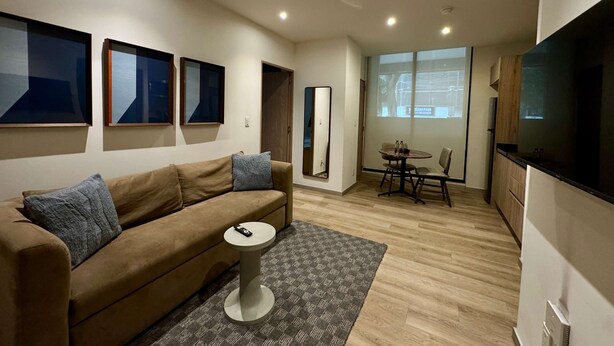 Una sala de estar moderna con un sofá, una mesita redonda y un televisor.
