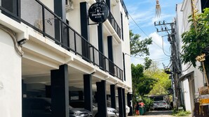 A building with a 'Double N Stay' sign, a covered parking area, and a narrow street. - Elimstay Hospitality Jimbaran Bali | Comfort, Pool & Tropical Ambience (Badung)