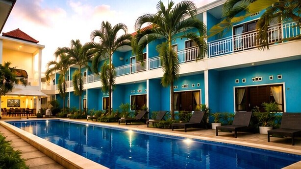 A hotel with a swimming pool, multiple balconies, and palm trees. - Elimstay Hospitality Jimbaran Bali | Comfort, Pool & Tropical Ambience (Badung)