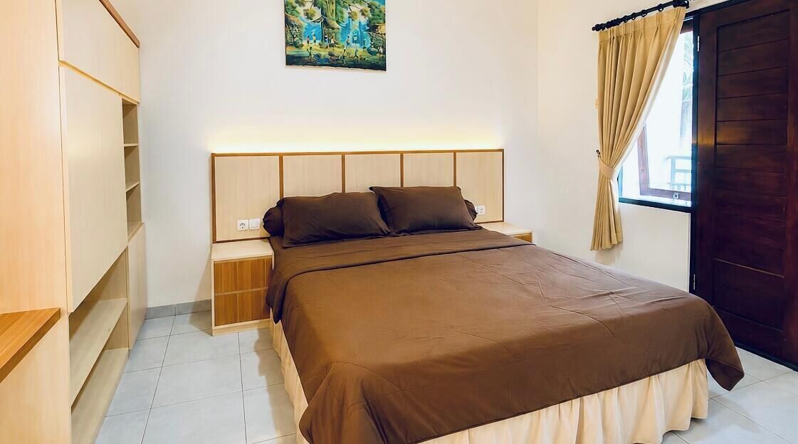 A bedroom with a bed, nightstands, a wardrobe, a painting, and a window with curtains.