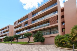 A multi-story hotel with balconies, a paved driveway, and landscaped greenery. - 2-Bedroom Apartment Herdade Dos Salgados, Shared Pool, Wi-Fi & Air Conditioning (Guia)