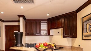 Una cucina con una grande isola, sedie in legno e una ciotola di frutta.