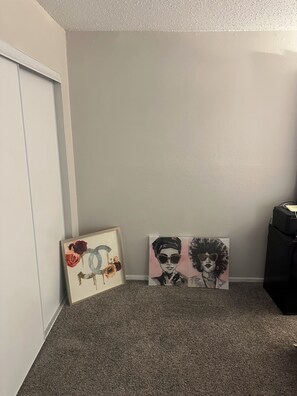 Ein Zimmer mit Teppichboden, einer weißen Tür und zwei gerahmten Kunstwerken an der Wand.