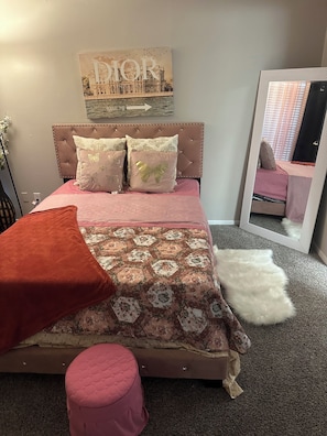 Ein Schlafzimmer mit Bett, Spiegel, Wanddeko und Teppichboden.